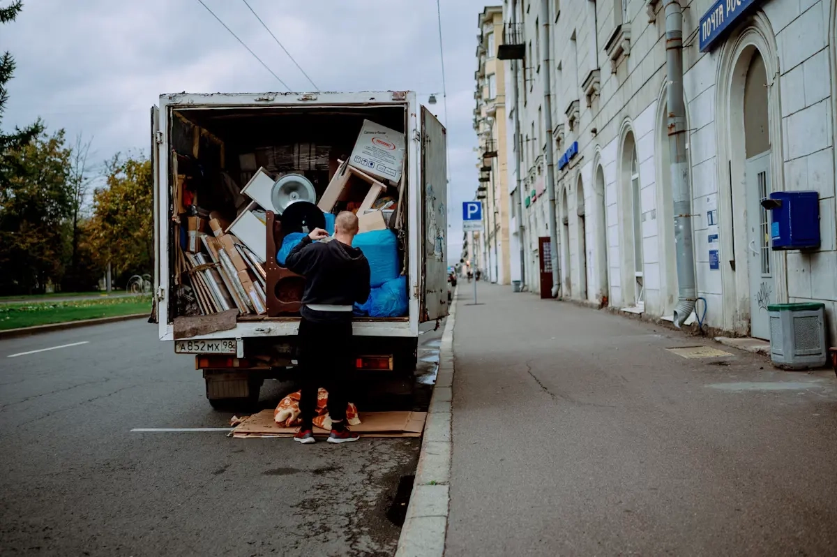 A worker loading household items into a box truck on a city street.
