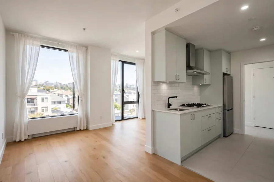 A bright, vacant apartment interior with an open living area and kitchen.